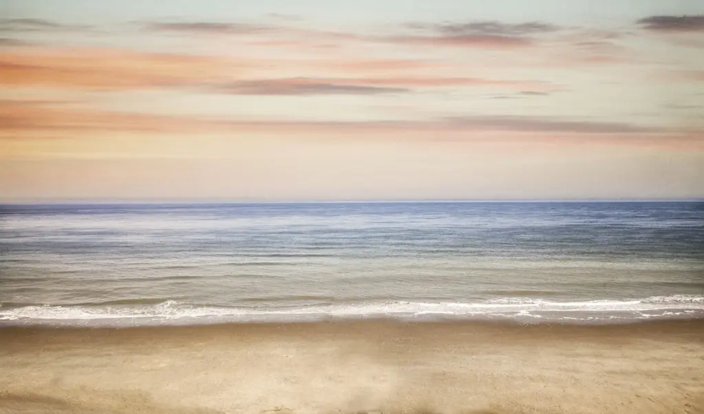 A calm sea meeting a soft pastel horizon at dusk