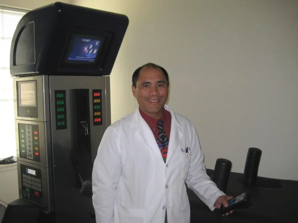 Dr. David Basco in a white coat beside the DRX9000 spinal decompression system in his office